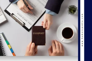 Two people at a desk completing a visa application process, with a passport being handed over, coffee cup, plant, and notebook nearby — symbolizing the journey of a digital nomad Bali lifestyle.